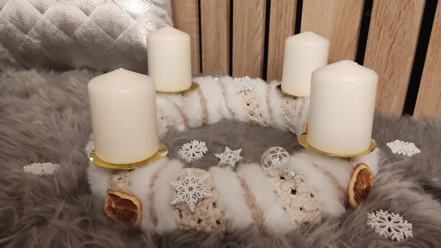 Four candles on a decorative wreath indoors.