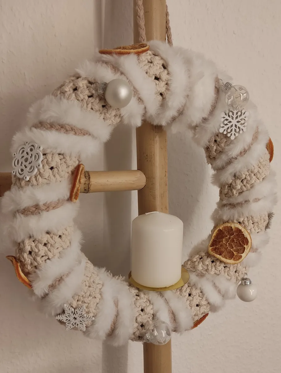Decorative wreath with candle on wooden ladder.