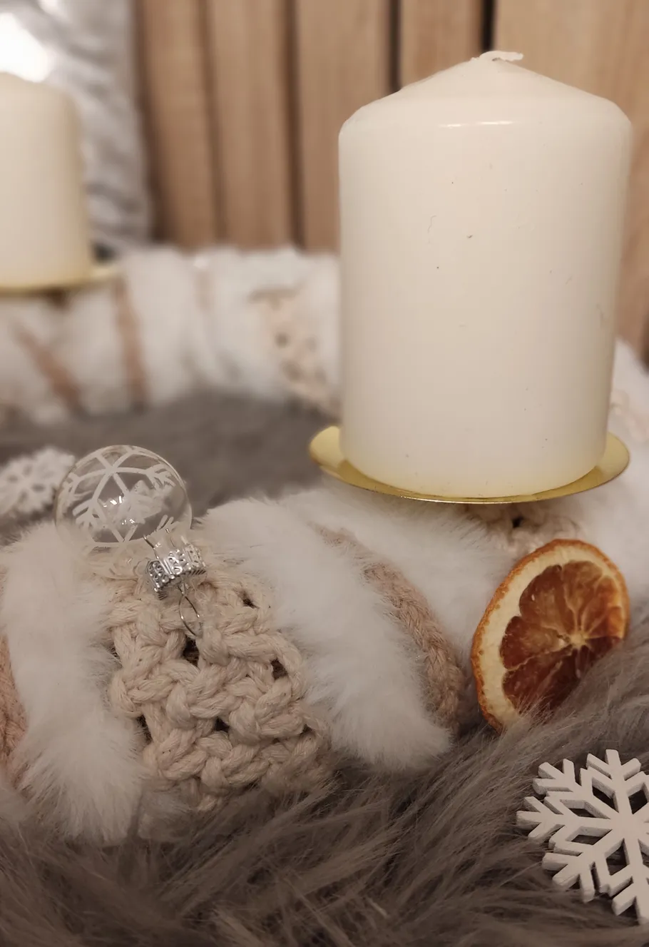 White candle on fluffy decorative wreath.