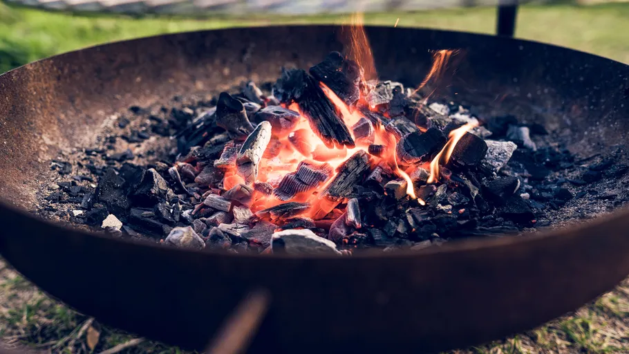 Burning charcoal in a metal fire pit outdoors.