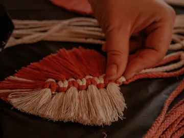 Hand greift bunte Faser, verziert textile Arbeiten auf Tisch.