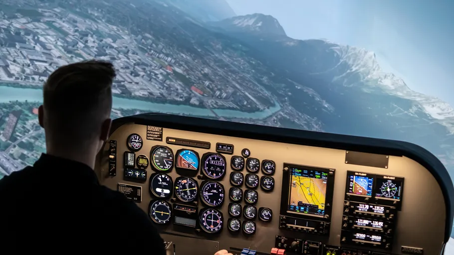 Person operating flight simulator cockpit.