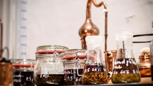Jars with liquids, copper distillery equipment, laboratory setting.