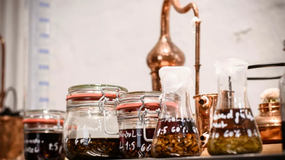 Jars with liquids, copper distillery equipment, laboratory setting.