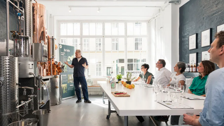 Person explaining distillery equipment to seated group.
