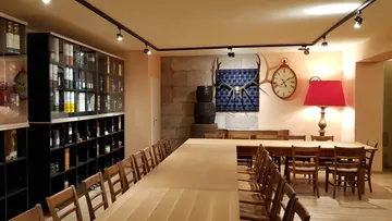 Raum mit Holztischen und Weinregalen.