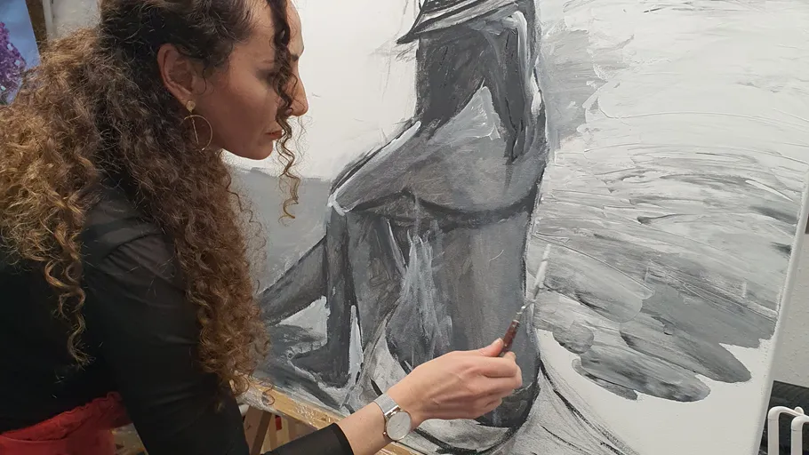 Woman painting on a canvas in a studio.