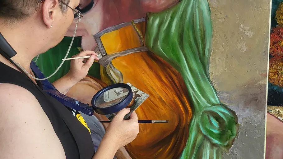 Artist paints detailed portrait on canvas.