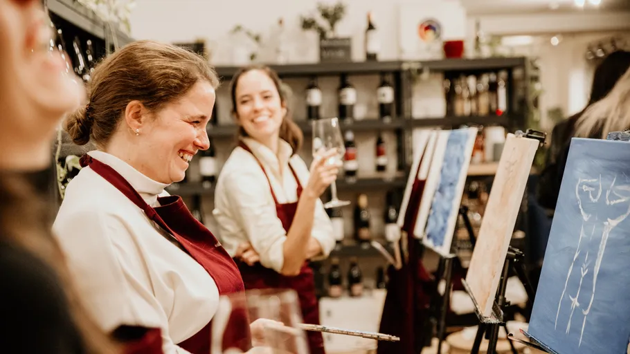 Women painting and laughing in art class.