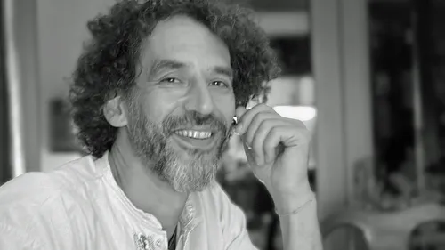 Smiling man with curly hair indoors.