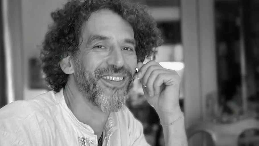 Smiling man with curly hair indoors.