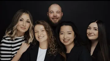 Five people smiling in a studio setting.