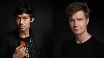 Two men posing against dark background.