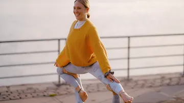 Frau in Yoga-Position im Freien am Wasser.