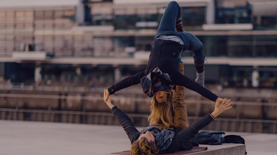 Two people doing acro yoga outdoors.