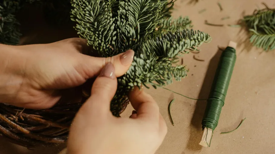 Hands crafting a wreath with green wire.