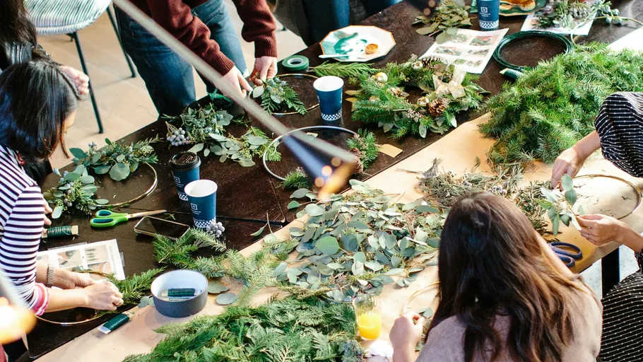 People crafting wreaths at a workshop table.
