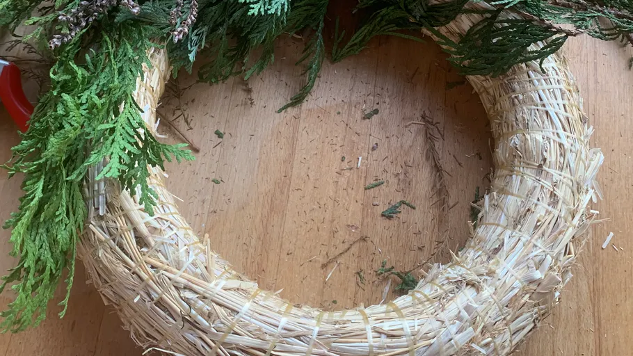 Half-decorated wreath on a wooden table.