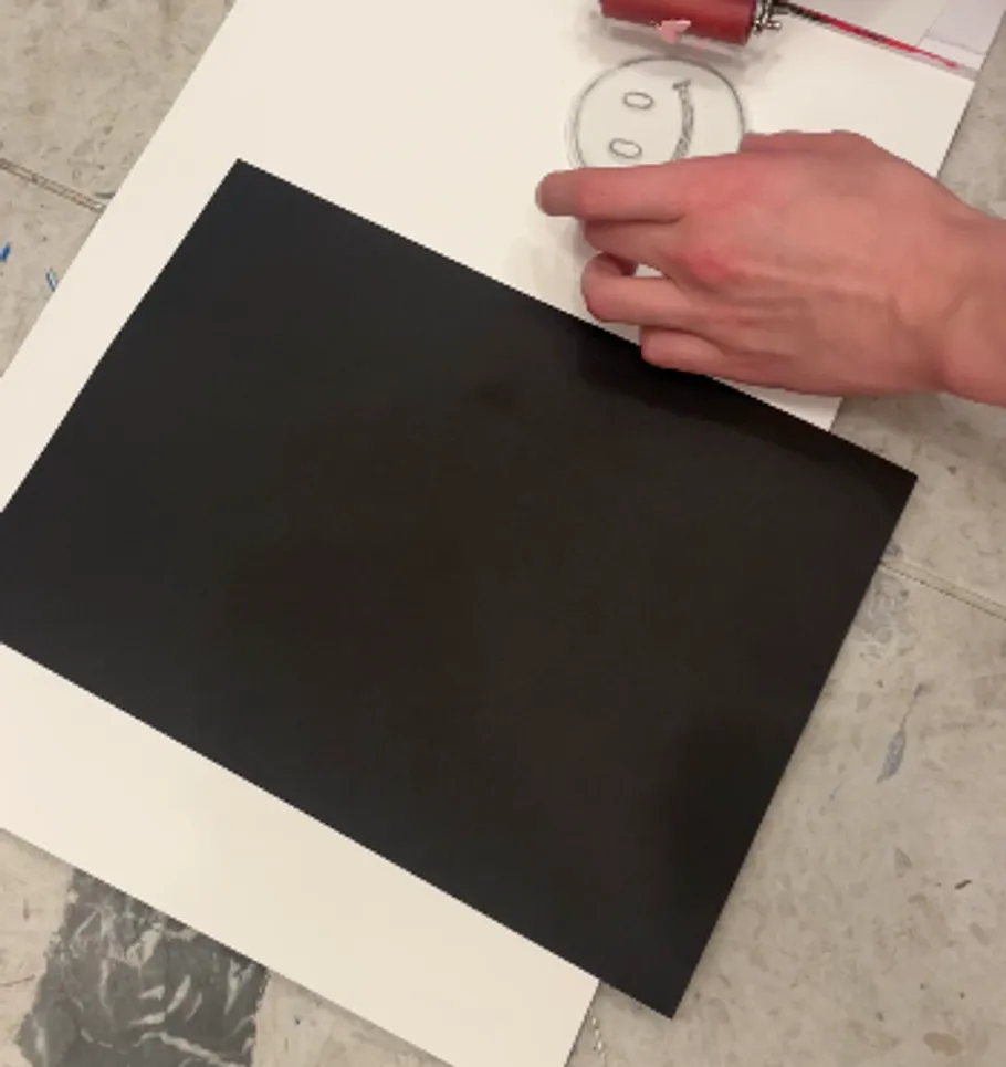 Hand zeichnet Smiley neben schwarzem Papier.