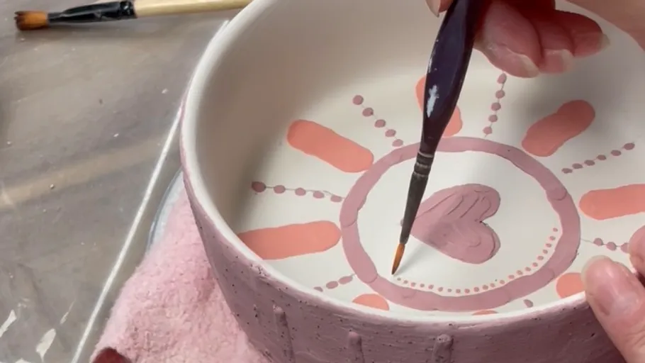 Hand painting a ceramic bowl interior.