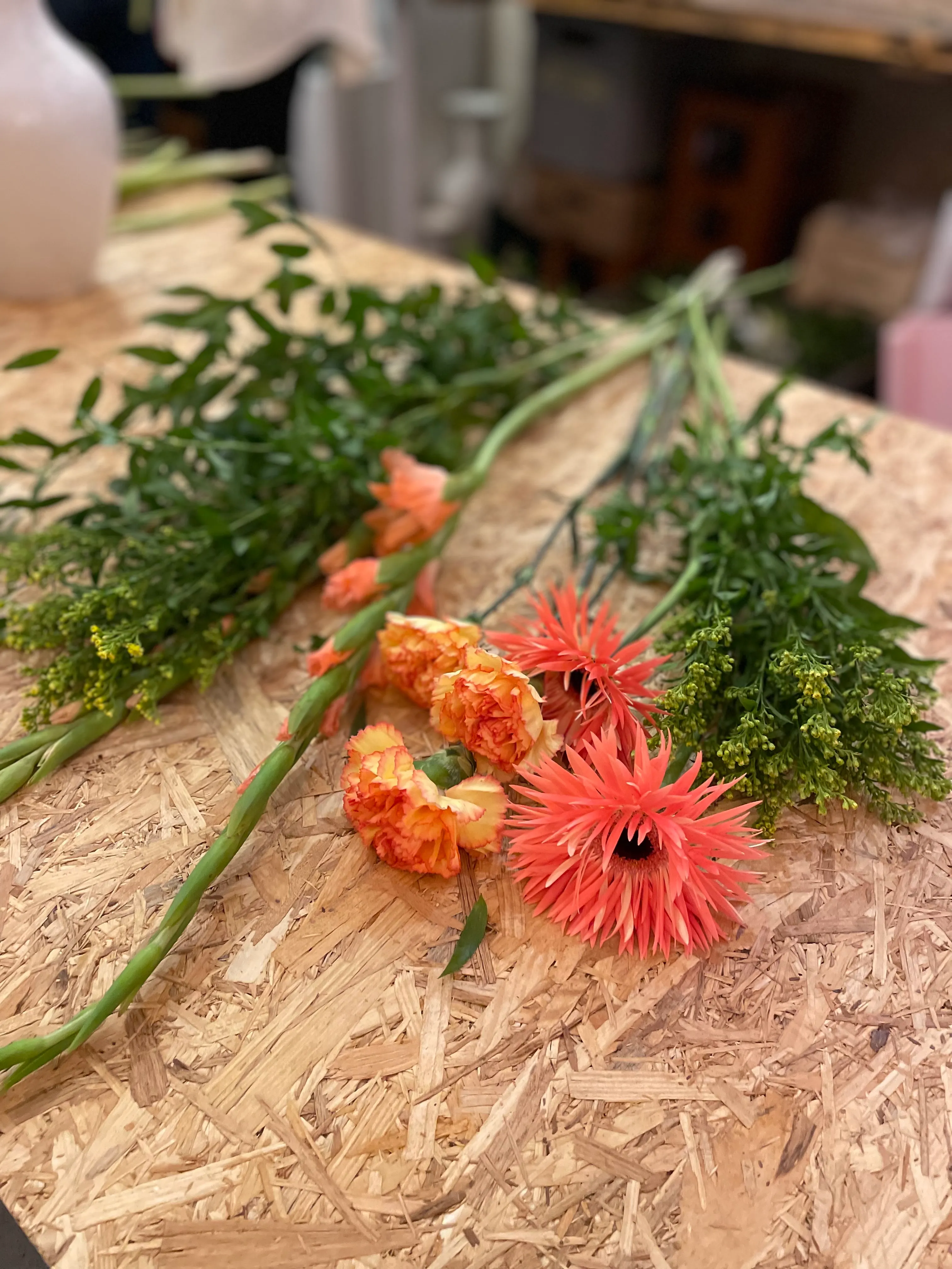 Blumen liegen auf Holztisch in Werkstatt.