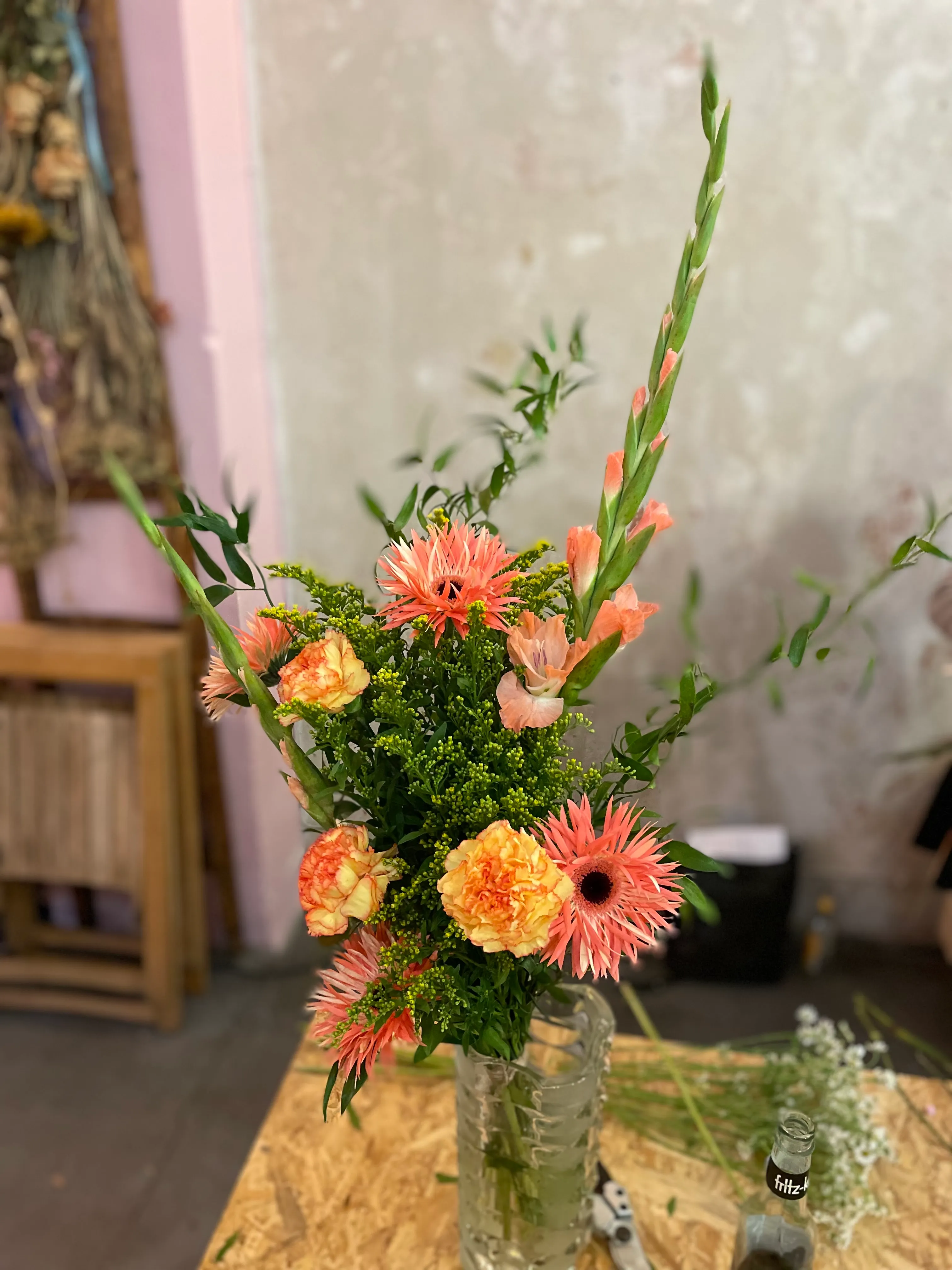 Oranger Blumenstrauß in einer Glasvase drinnen.