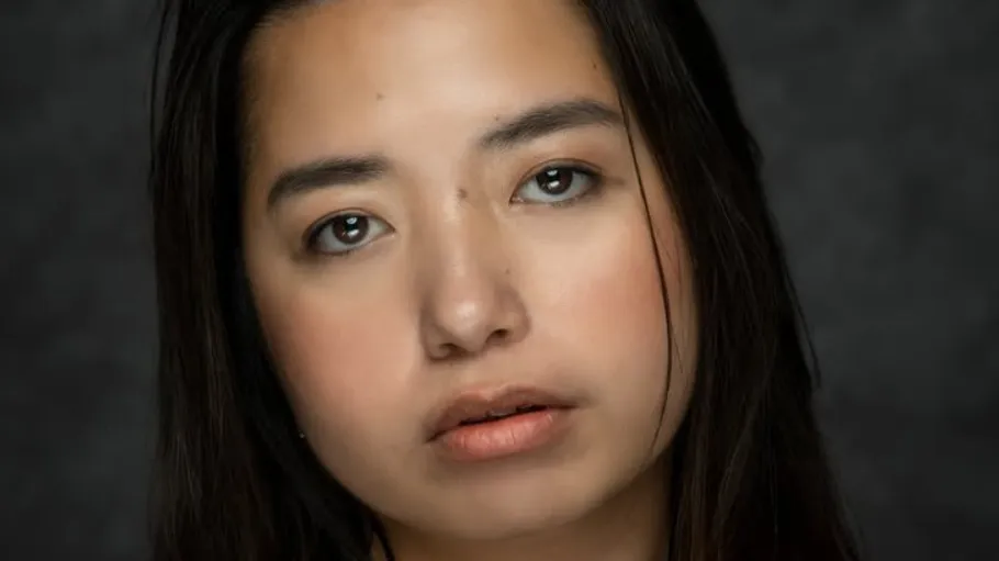 Woman looking at camera, gray background.