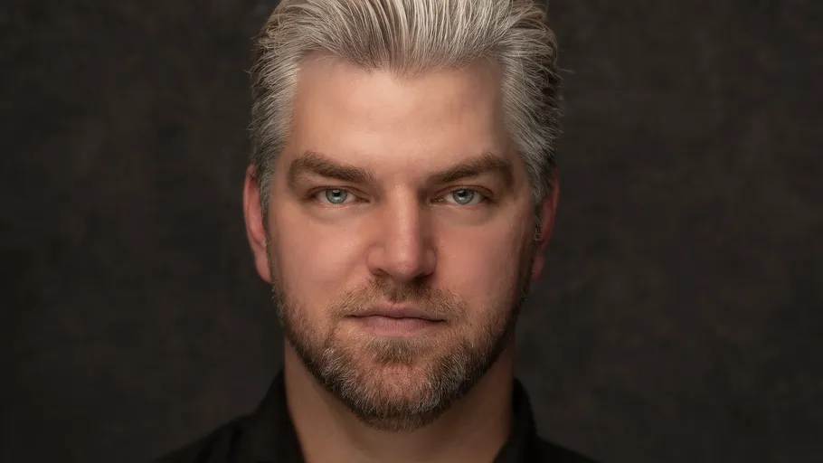 Man with gray hair against a dark background.