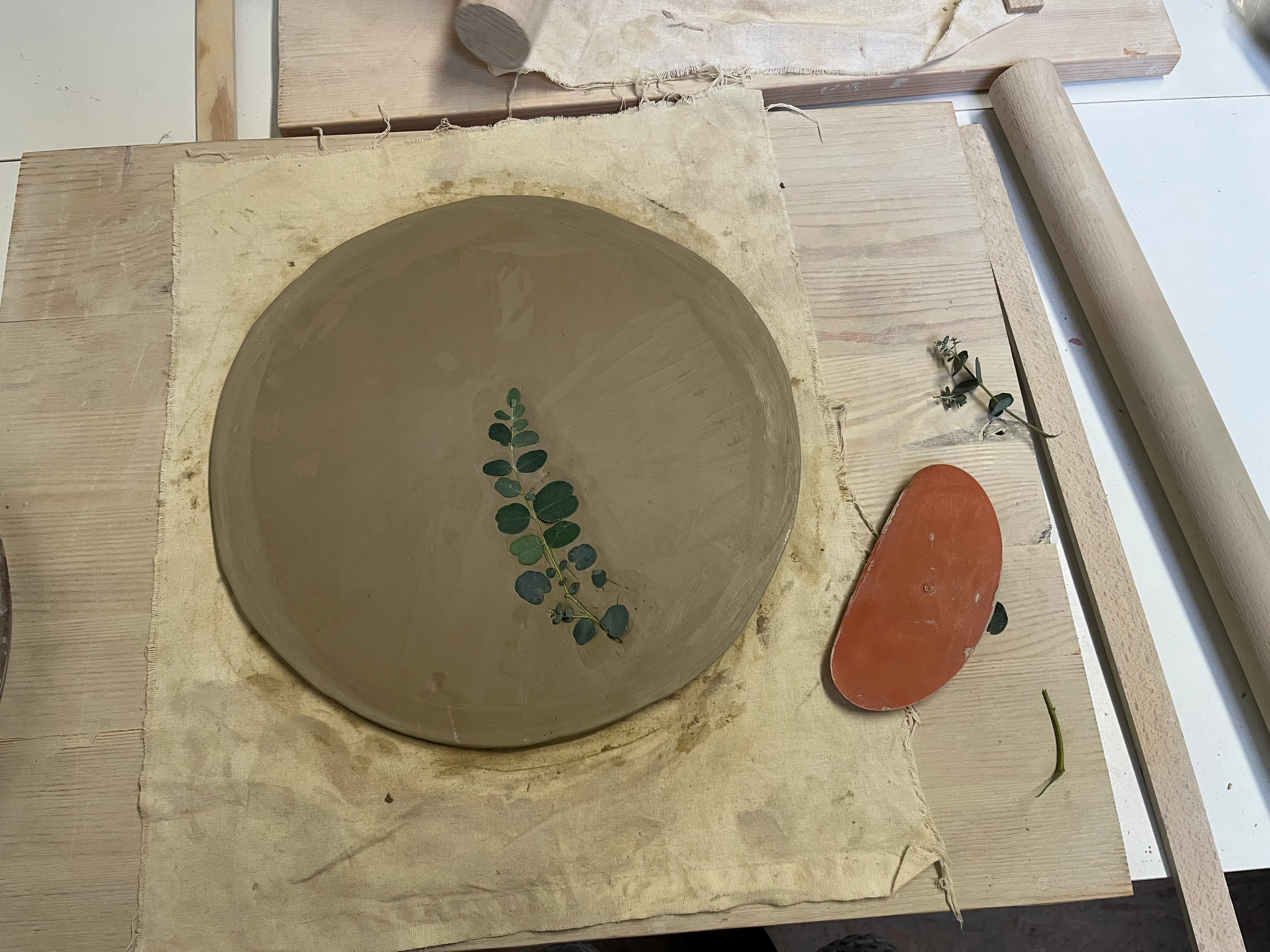Clay dish with leaves lies on a table.