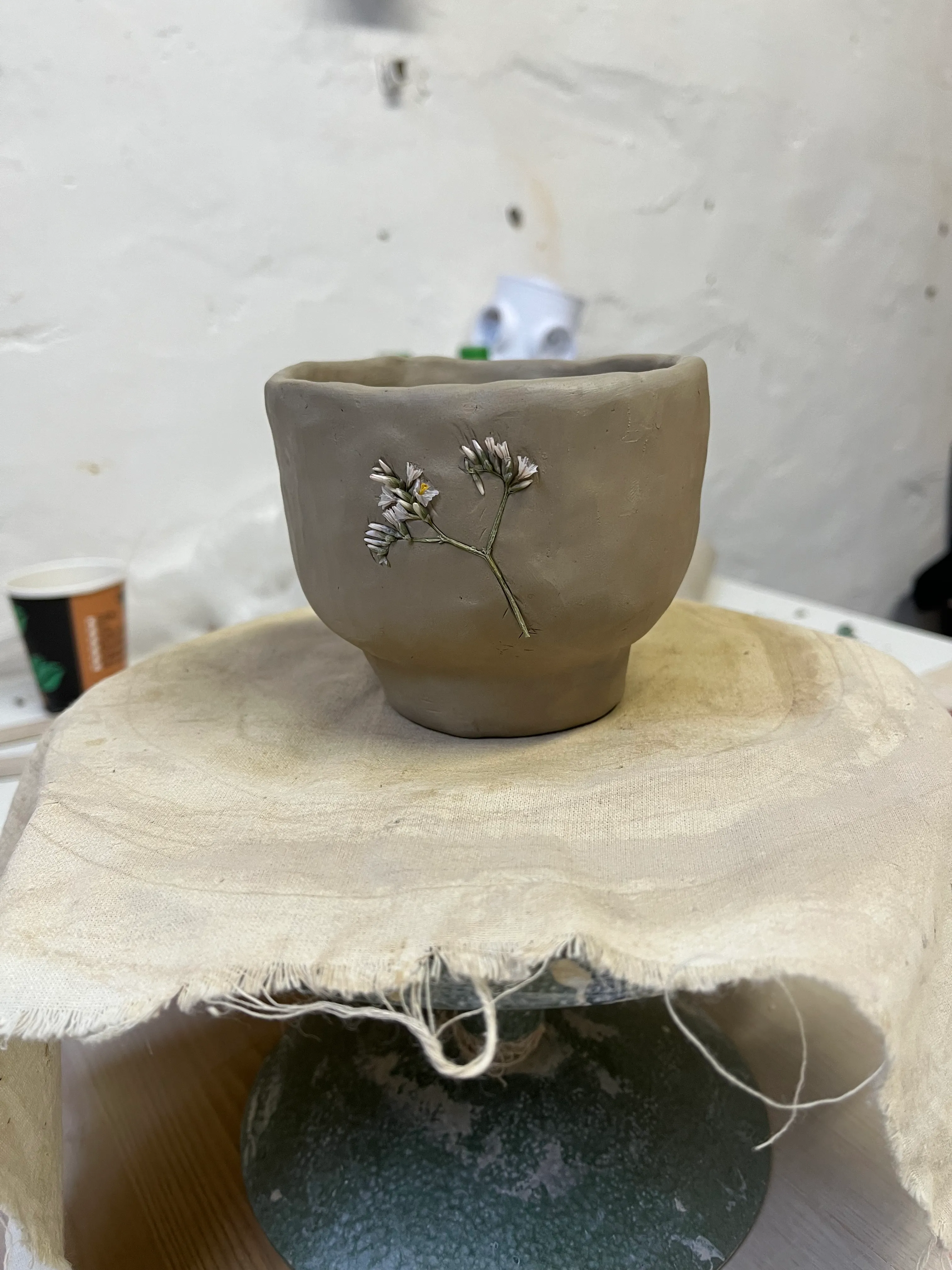Clay cup with flower imprint on table.
