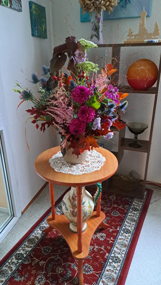 Blumenstrauß auf Holztisch in Zimmerecke.