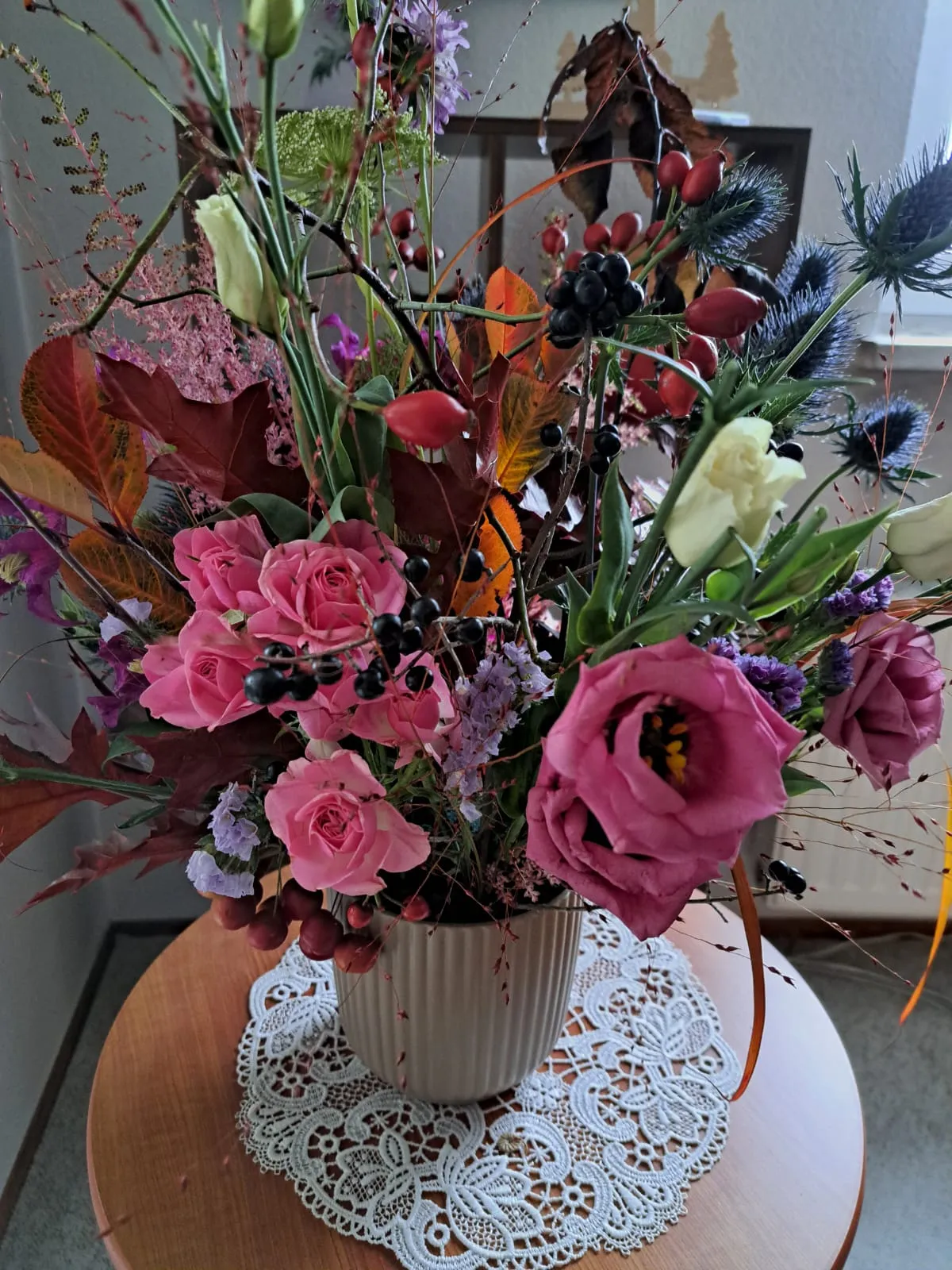 Blumengesteck mit Rosen auf einem Tisch.