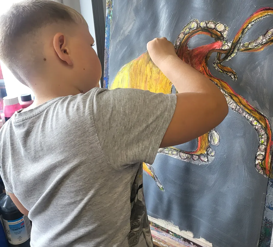Child painting octopus on canvas indoors.