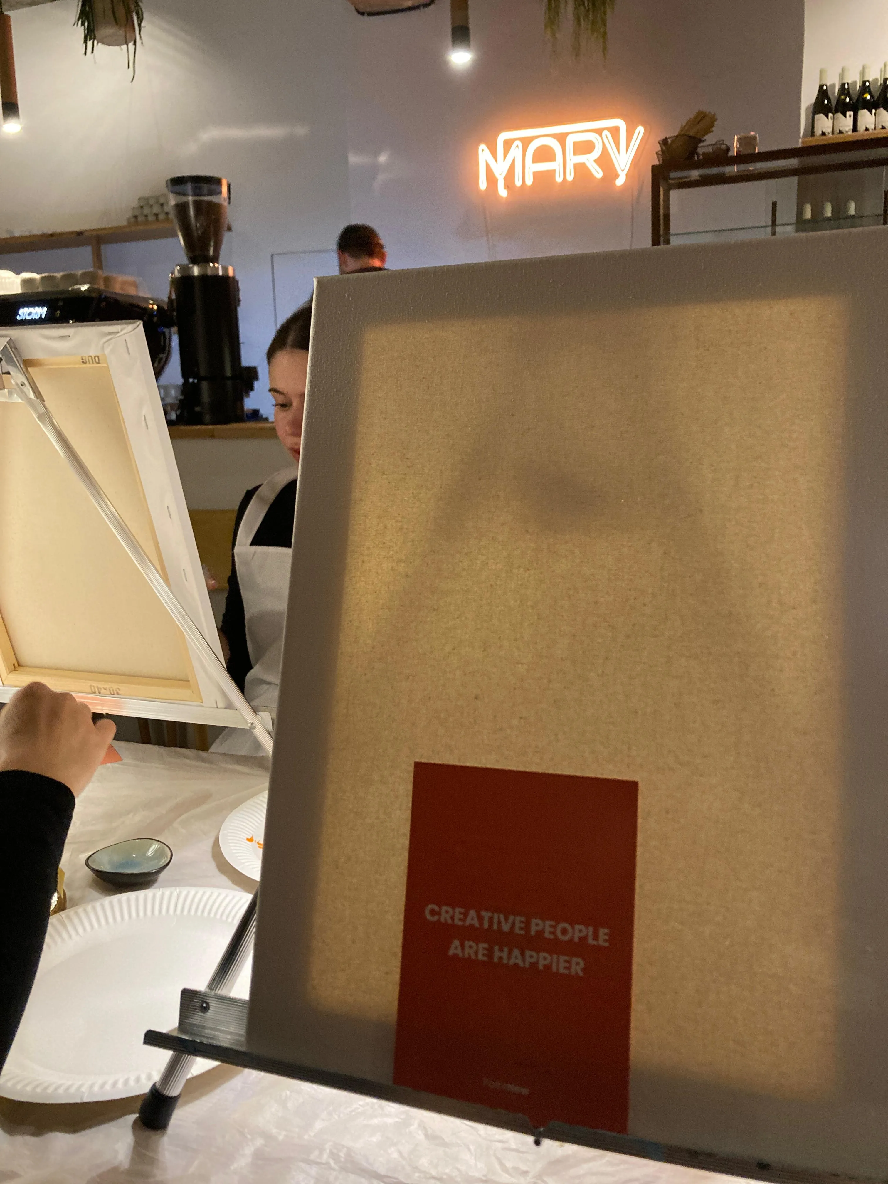 Canvas on easel in a cafe setting.