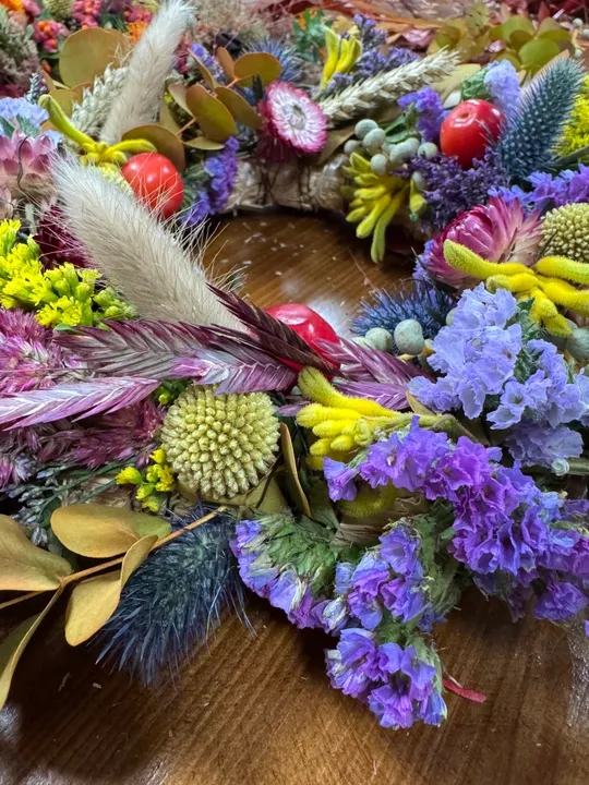 Bunter getrockneter Blumenkranz auf Holztisch.