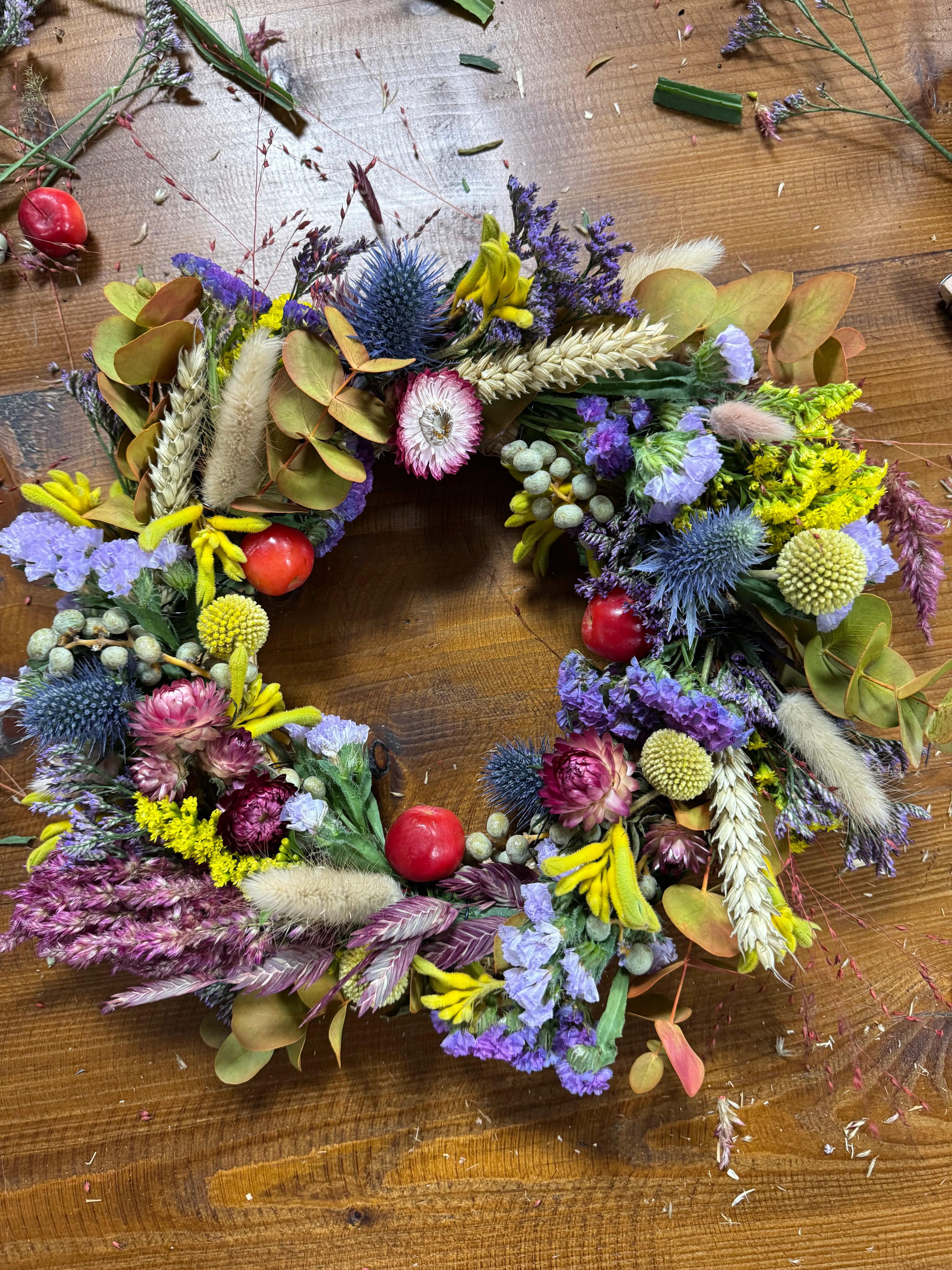 Bunter Blumenkranz auf Holztisch.