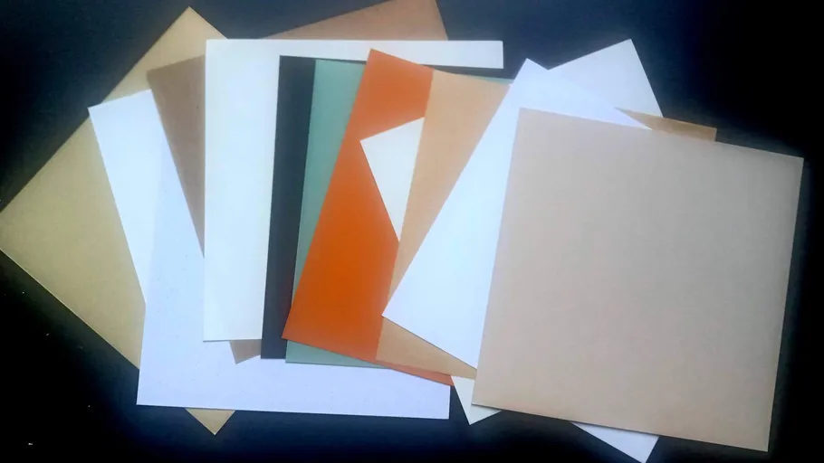 Assorted colored paper sheets on a dark surface.