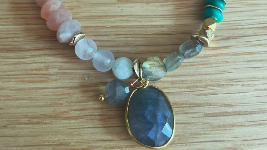 Perlenkette mit blauem Anhänger auf Holz.