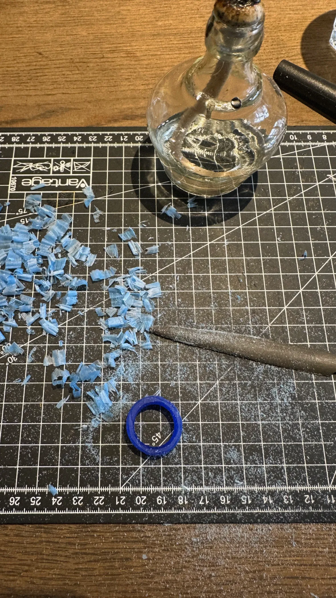 Blue carving scraps on cutting mat with tools.
