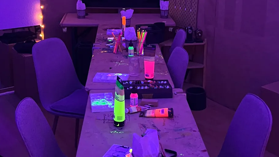 Table with glowing art supplies under UV light.