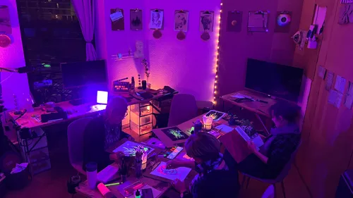 People drawing in dark room with purple lighting.