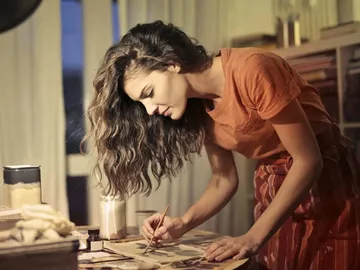 Young woman paints concentratedly at a table in the studio.