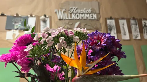 Blumenstrauß mit Willkommen-Schild im Hintergrund.