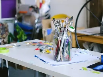 Brushes in a glass, standing on a table, artistic environment.