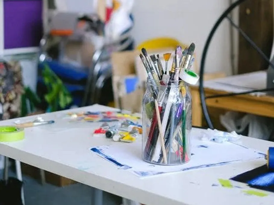 Brushes in a glass, standing on a table, artistic environment.