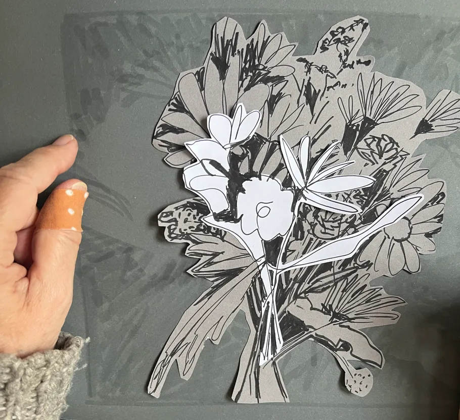 Hand hält Papierblumen auf grauer Oberfläche.