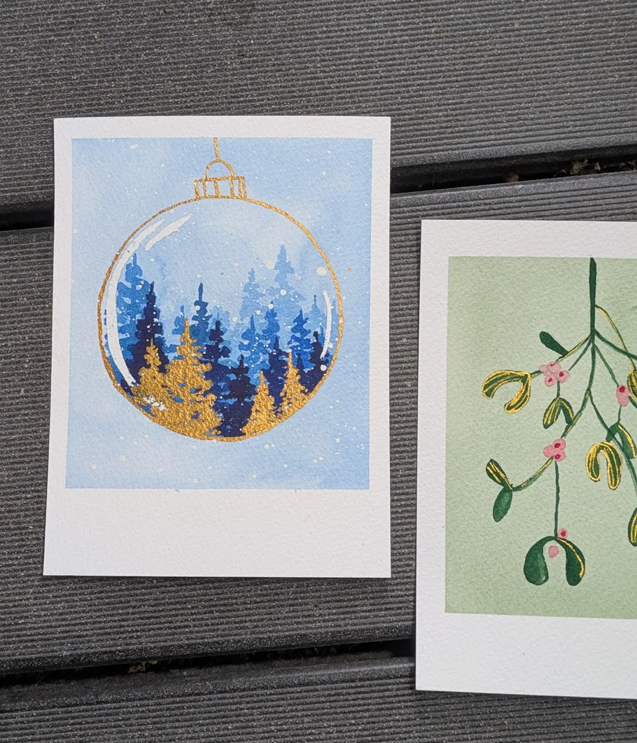Paintings of ornaments and mistletoe on wood.