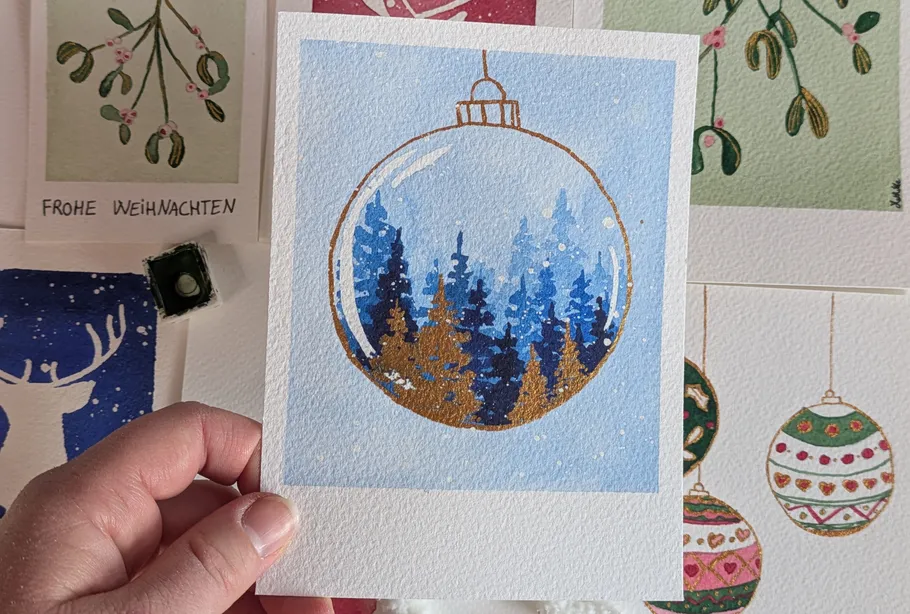 Hand holding painting of forest in ornament.