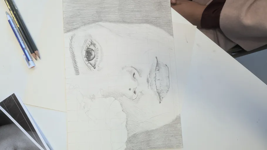 Pencil drawing of a face on a table.