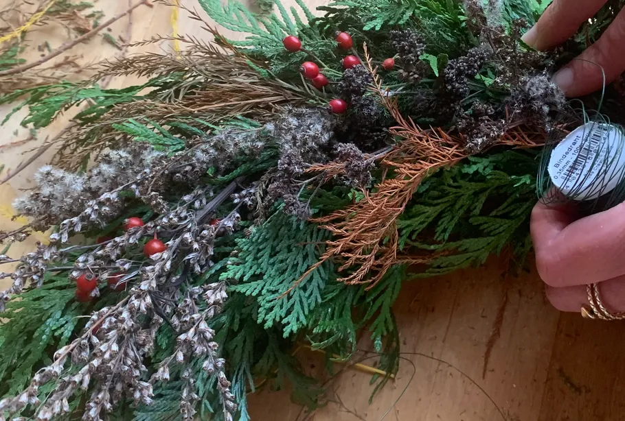 Hands arranging foliage with red berries.